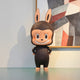The Monster Freckles Mega Labubu Sculpture by Giant Sculptures is a 160cm collectible figure with a mischievous grin, big eyes, and expressive face, dressed in a furry black costume with ears, set before abstract geometric wall art.