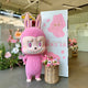 The Monster Mega Labubu Sculpture - 160cm by Giant Sculptures, featuring sharp teeth and lifelike faux-fur, stands beside a flower basket and tall pink-and-white display in a modern indoor space decorated with more flowers.