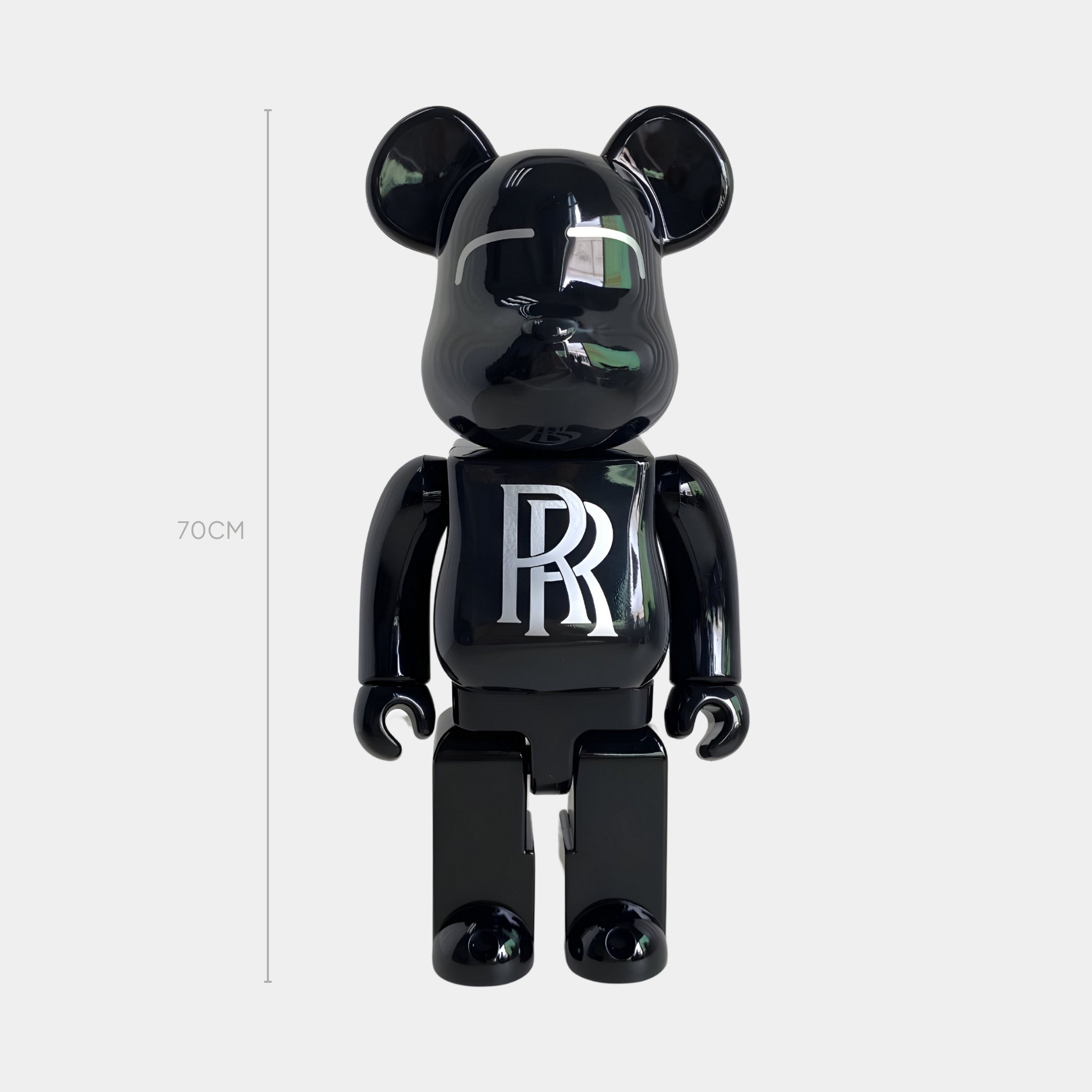 The Midnight Crest Bear Sculpture - 70cm by Giant Sculptures is a glossy, black bear figure with round ears and a white RR logo on its chest, crafted from piano-gloss resin and inspired by the Rolls-Royce emblem.