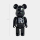 The Midnight Crest Bear Sculpture - 70cm by Giant Sculptures is a glossy, black bear figure with round ears and a white RR logo on its chest, crafted from piano-gloss resin and inspired by the Rolls-Royce emblem.