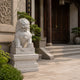 White marble guardian lion on its three-tier plinth by a carved stone screen