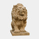 Brown stone lion seated on a flat slab, jaws closed and the mane cut in deep locks
