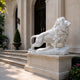 White marble lion in profile mid-stride on its rock-faced slab