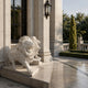 White marble lion crouching low with jaws wide on a house terrace