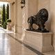 Bronze lion with a cub between its forelegs on its cream marble plinth