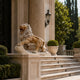 Beige stone lion roaring with a forepaw lifted onto its rock outcrop