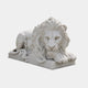 White marble lion couchant with crossed paws projecting past the plinth edge