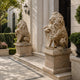 Beige marble lion seated with a forepaw over its scrolled cartouche