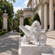 White marble winged lion with its paw on a shield carved with a lion mask
