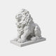 White marble lion seated with head turned and forepaws spread forward