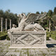 Beige stone winged lion couchant with a crown before its forepaws
