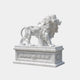 White marble lion standing on a pedestal carved with leaf swags and a rosette
