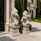 The two marble lions with their cartouches on pink pedestals by a gate