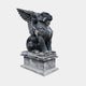 Black marble winged lion seated on a fluted pale grey pedestal