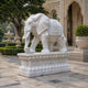 White marble elephant with a carved roundel on its cloth, trunk holding a bowl