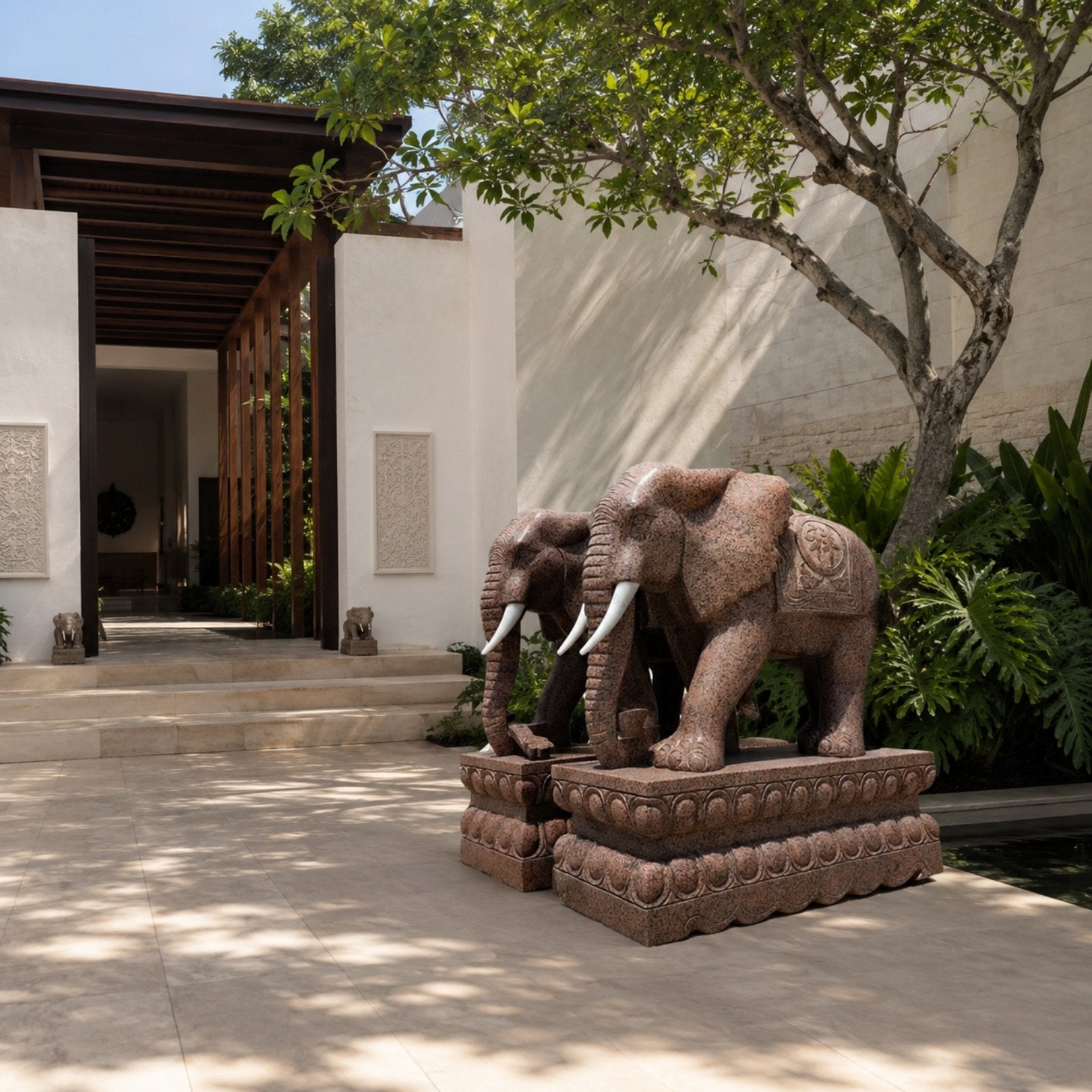 Red granite elephant with white tusks and a carved saddle-cloth