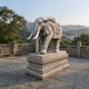 Grey granite elephant with a mask-carved cloth and pale tusks