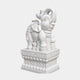 White marble elephant with its trunk curled overhead, standing among carved coins