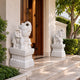 White marble elephant seated with its trunk raised over stacked coins