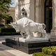 White marble charging bull statue in a paved forecourt