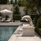 White marble leaping dolphin statue beside a swimming pool