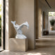 Two white marble dolphins shown indoors in a limestone gallery