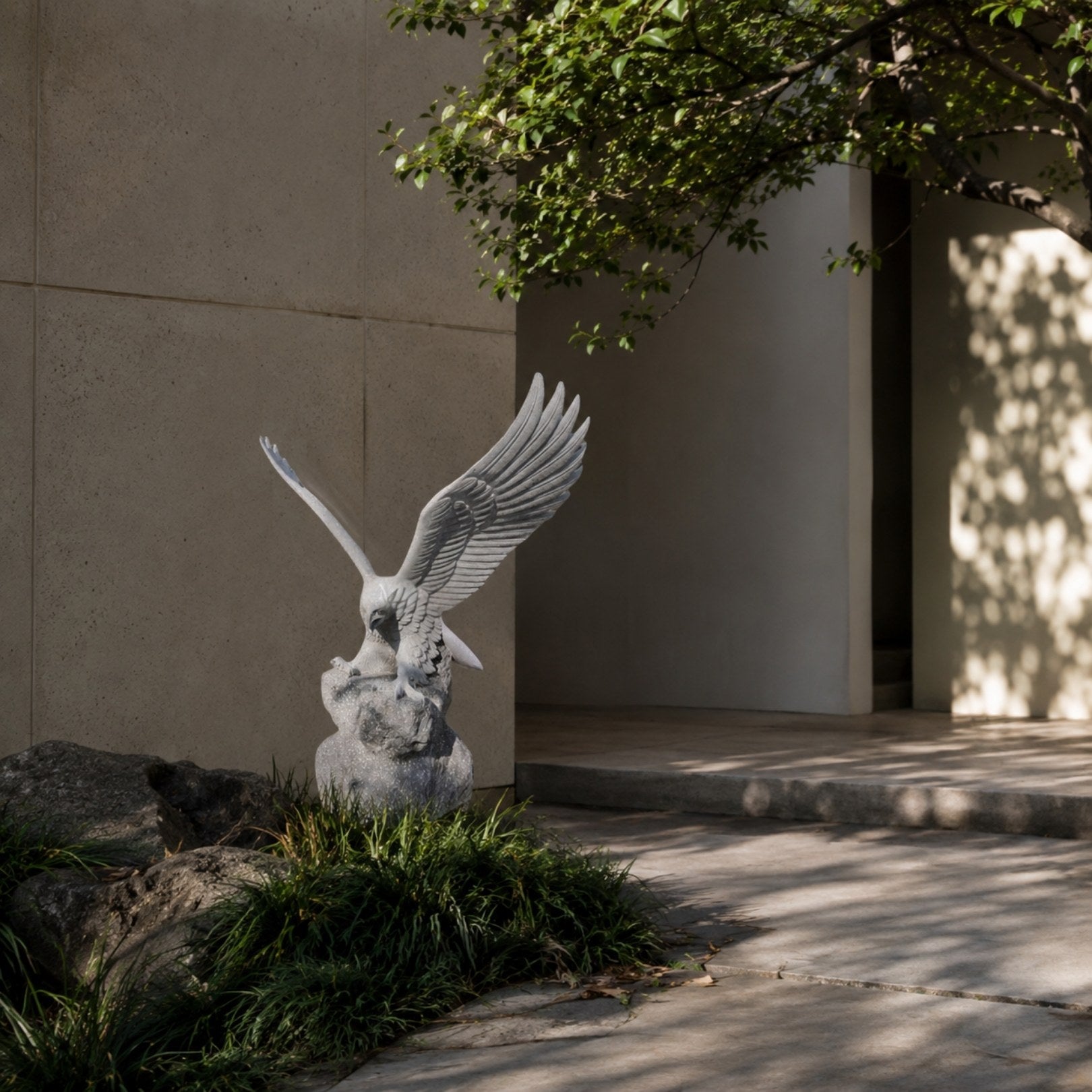 Grey marble eagle shown in a planted bed beside a paved courtyard