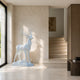 White marble stag shown indoors on its oval base beside a staircase