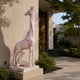 Pink marble giraffe and calf shown beside a modern entrance
