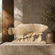 Beige marble arowana on its slab, shown indoors against a stone wall