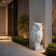 Faceted white marble owl on its plinth, lit beside a modern entrance