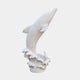 White marble dolphin leaping from a carved wave, flukes dropping in beneath