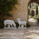 Two white marble sheep on paving, one grazing and one standing