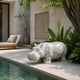 White marble hippo standing on its own feet on poolside paving