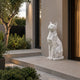 Faceted white marble cat on its slab beside a modern entrance