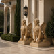 Two beige marble winged sphinxes, each on its own slab, at a forecourt
