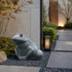 Grey granite frog shown in a gravel bed at a lit entrance