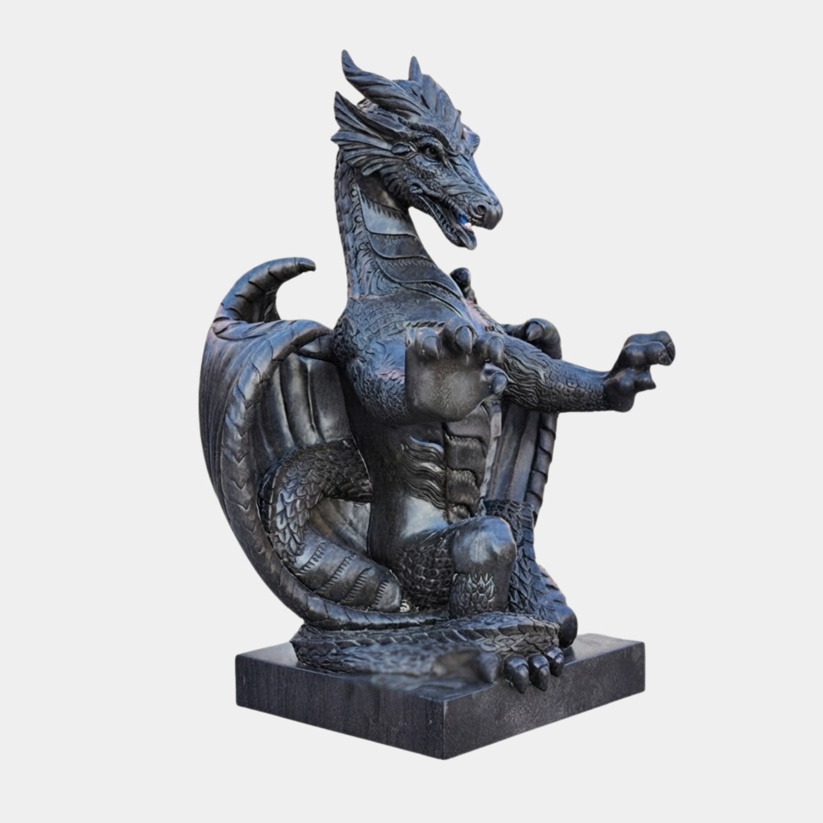 Near-black marble dragon seated with membranous wings and forepaws raised