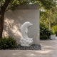 White marble dolphin on its slab against a stone wall