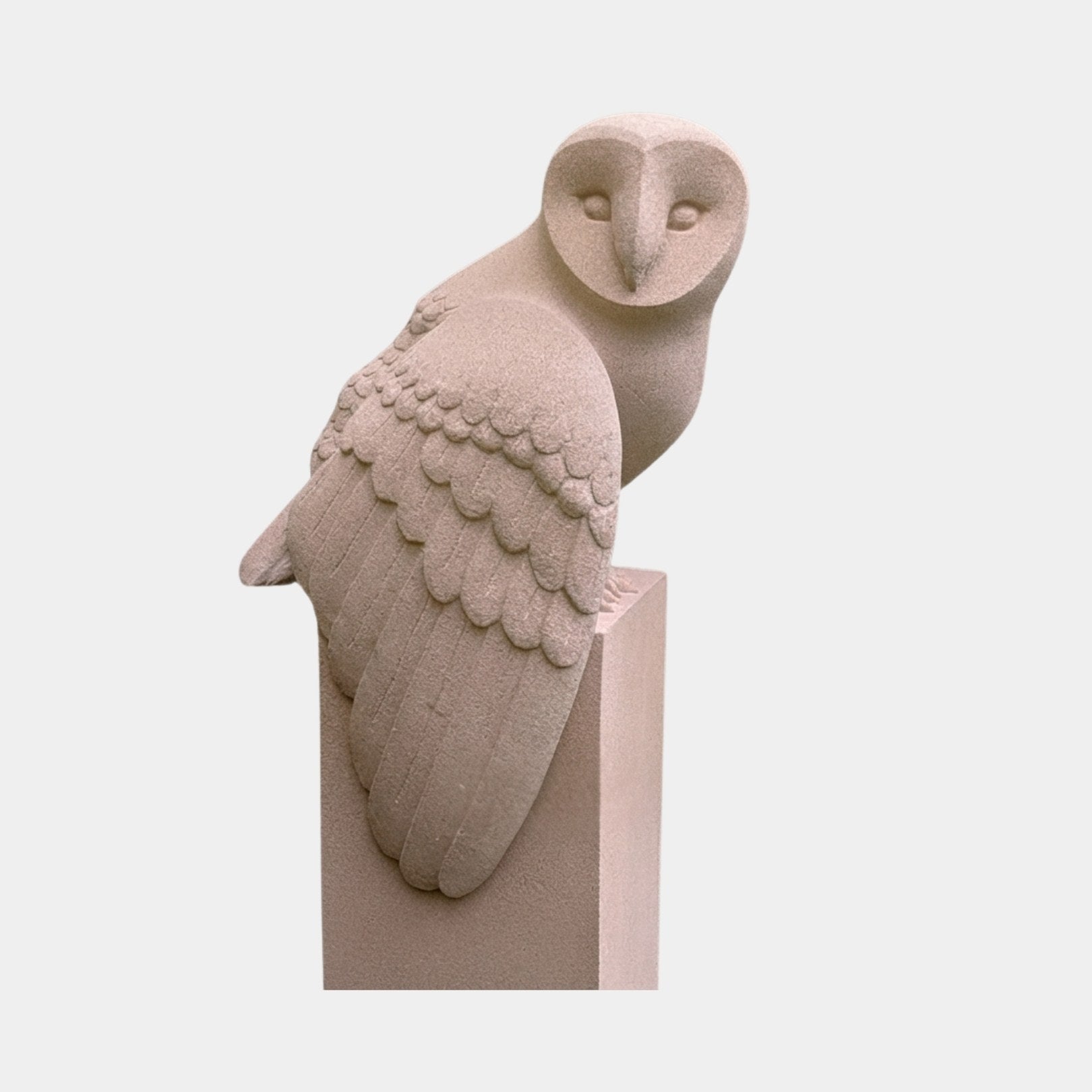 Buff sandstone barn owl perched on a tall square post