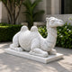 White marble camel on its slab beside clipped hedging