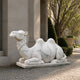 Plain white marble camel on its slab beside a portico