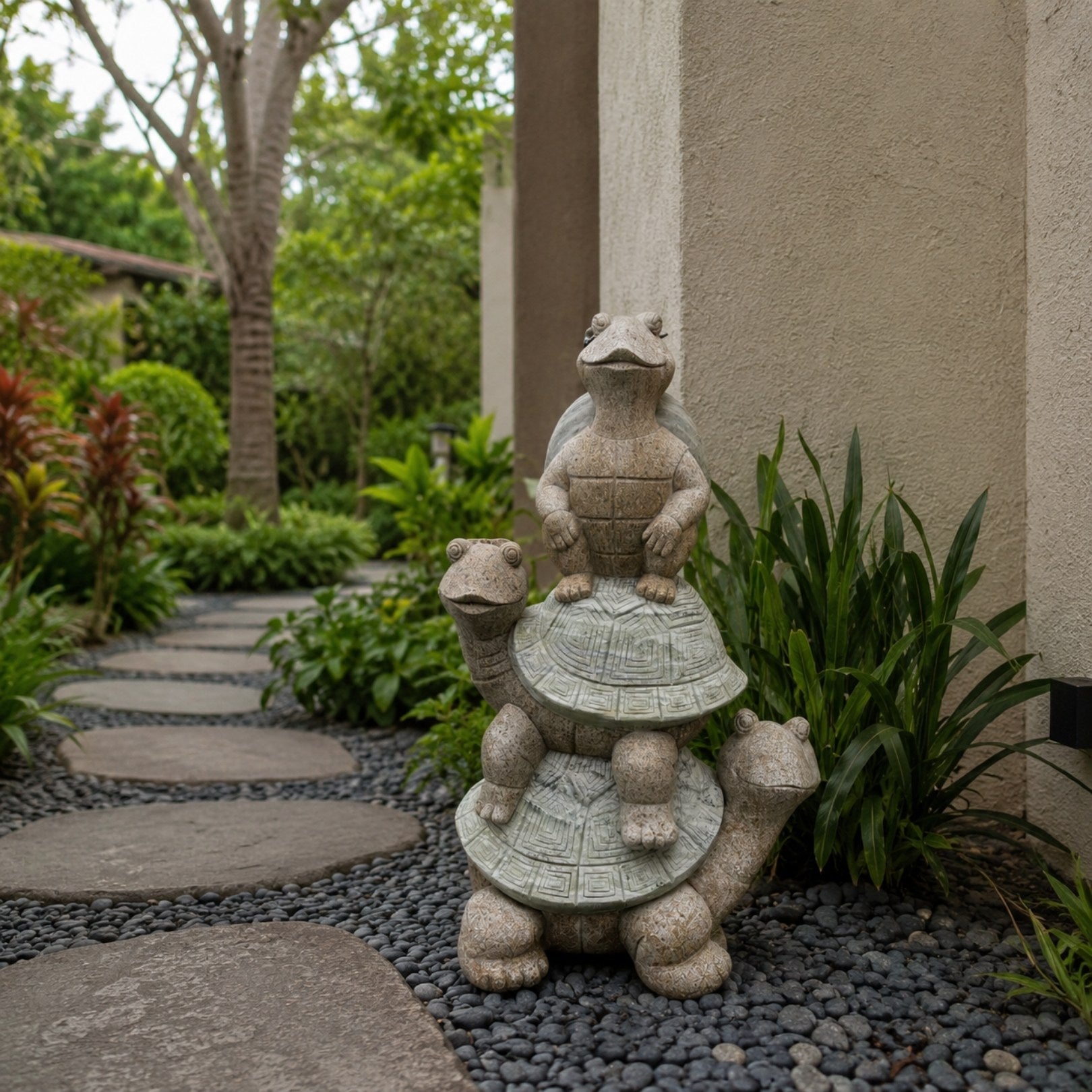 The stacked turtles standing on a pebble bed beside a planted garden path