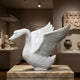 The white marble swan indoors in a gallery, wings lifted and bill open