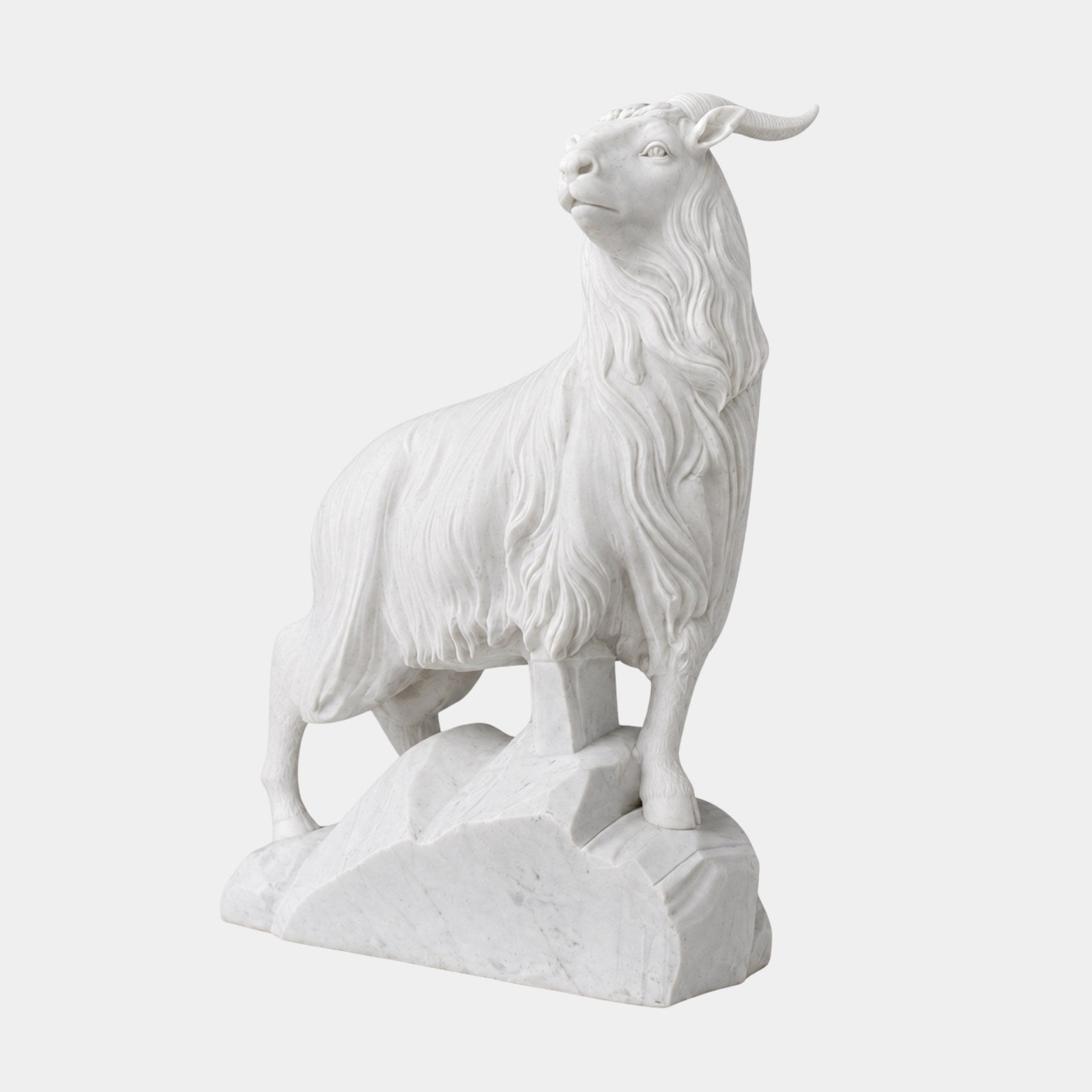 White marble sheep standing on carved rock with long ringed horns
