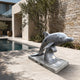 The grey dolphin on a travertine terrace beside a swimming pool