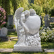 Marble angel and heart memorial shown on a cemetery plot in summer