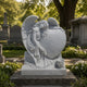 Grey marble angel and heart memorial shown in an established churchyard