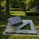 Marble open book ledger shown resting on a stone kerb surround in a cemetery lawn