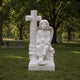 Marble child angel and cross memorial shown on a churchyard lawn